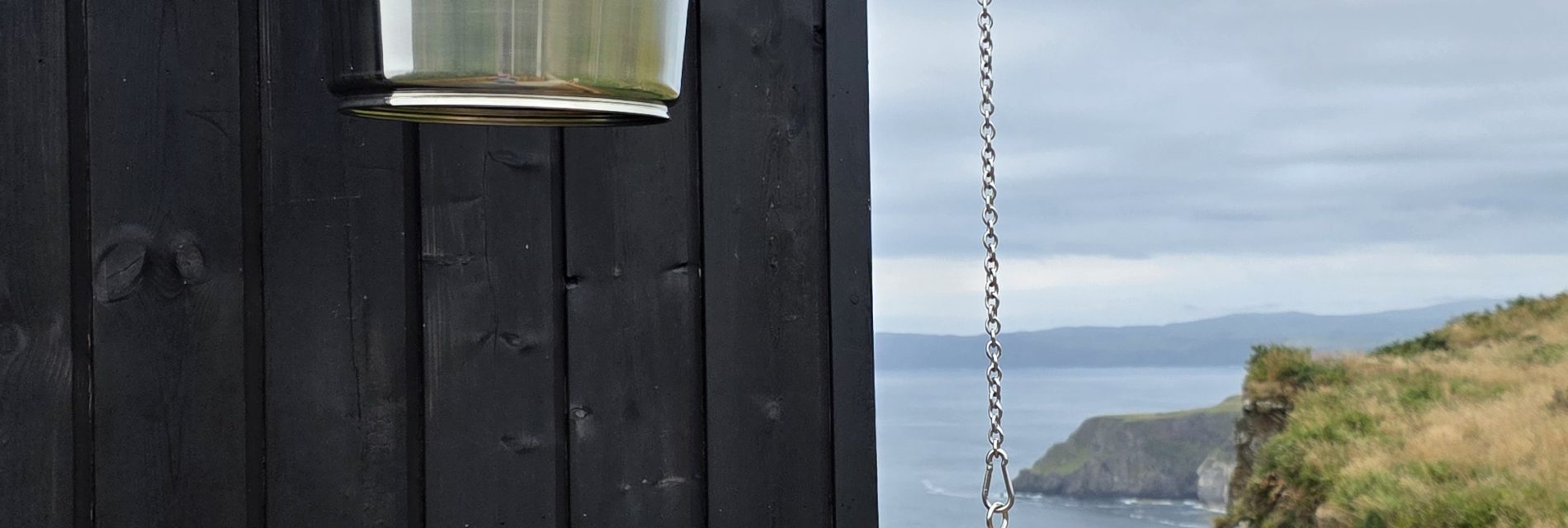 Outdoor cold-water bucket shower beside the timber-clad coastal sauna